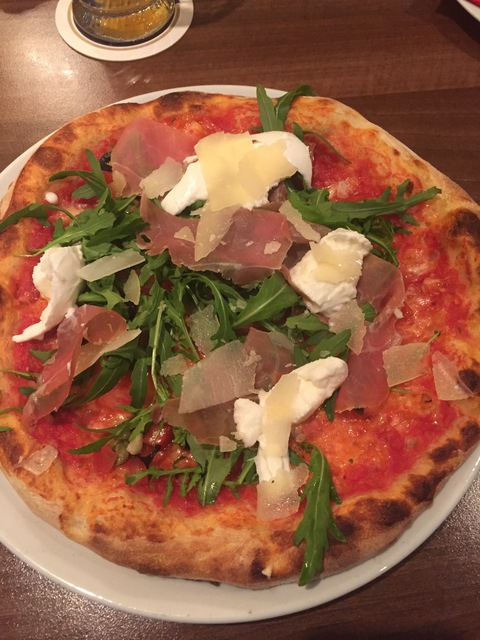 a pizza with rucola, parmesan cheese ribbons, buffalo mozzarello, and prosciutto